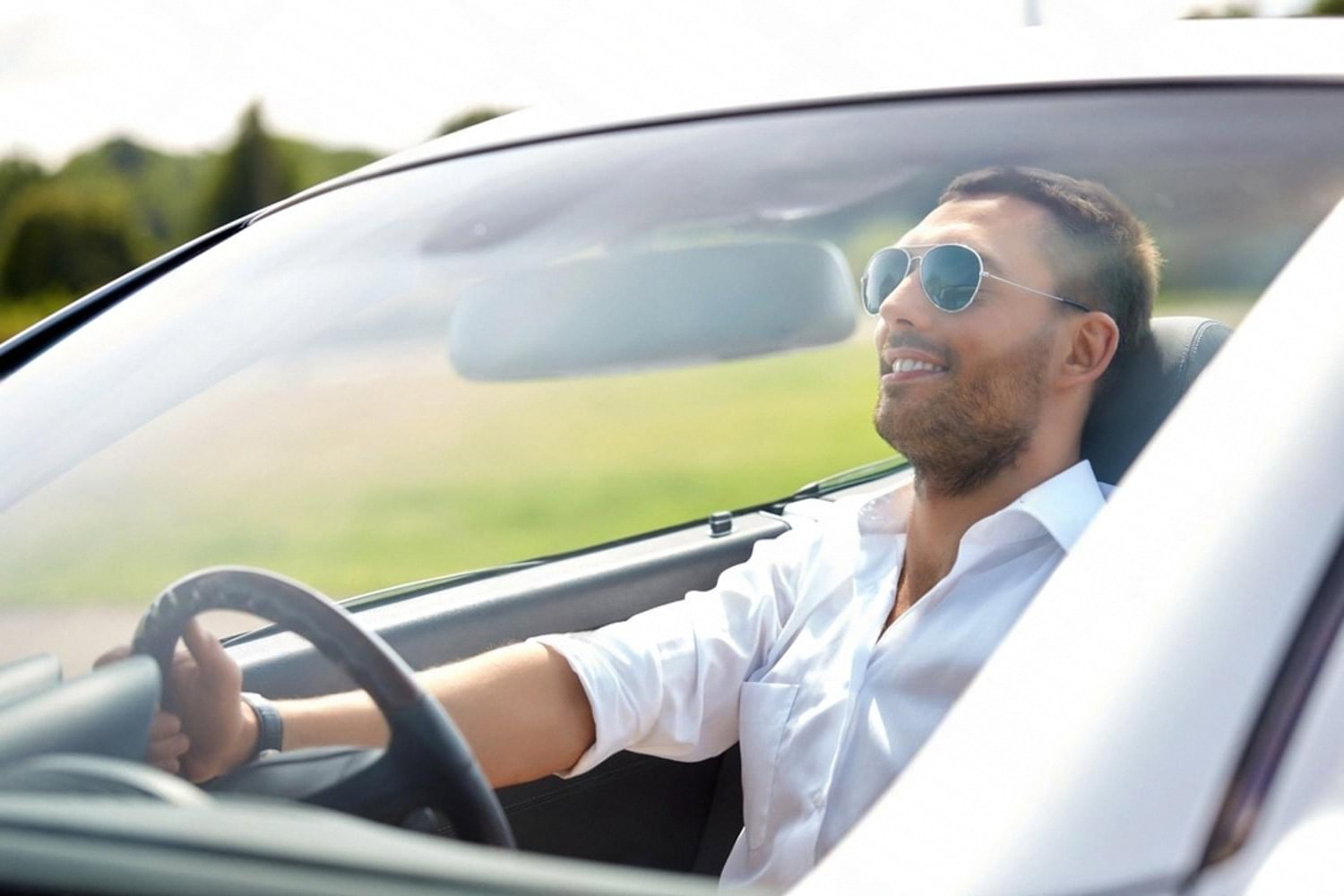 Man driving a white car with a clean, glossy exterior finish