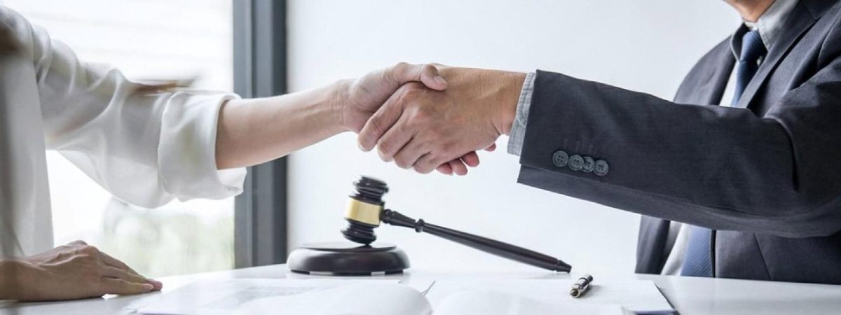 Business partners shaking hands over a commercial contract with a gavel on the desk