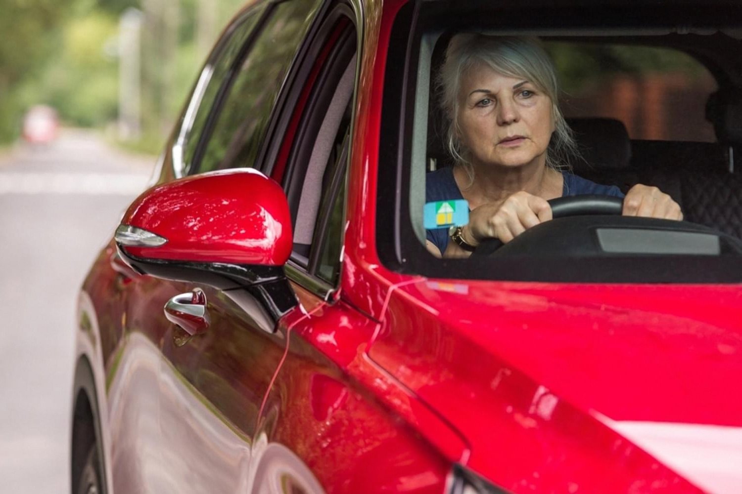 Older driver in a well-kept red car showing preserved factory shine